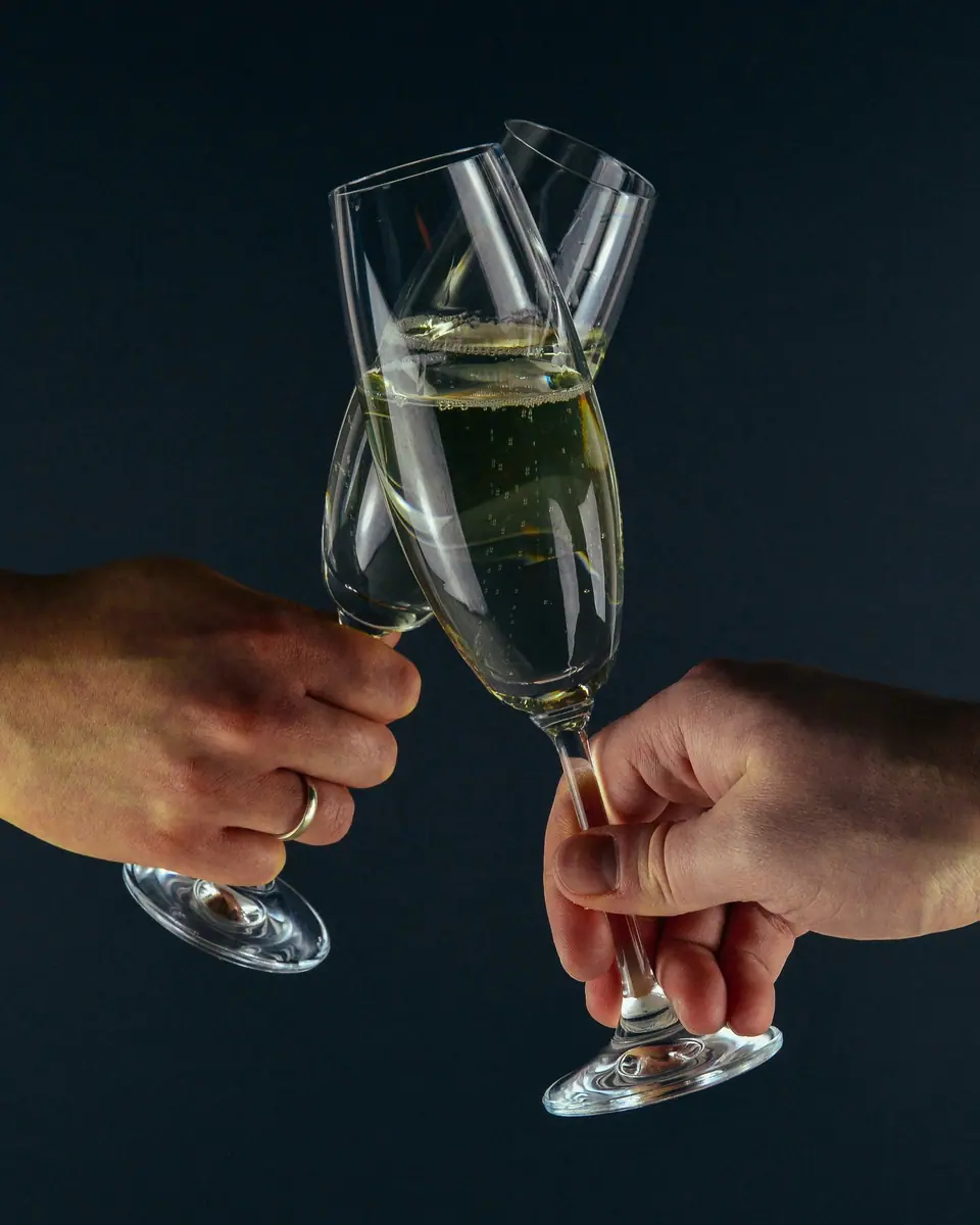Duas mãos brindando com taças de espumante